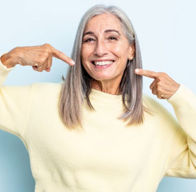 Happy older woman pointing at her smile