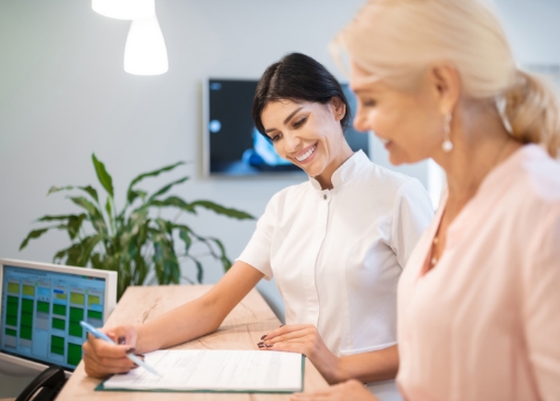 Receptionist showing a patient where to sign on a form