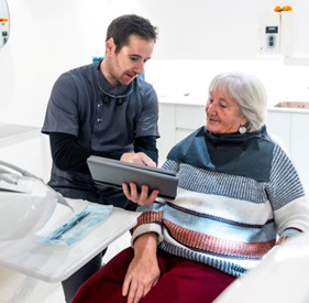 Oral surgeon and senior patient talking during dental implant consultation